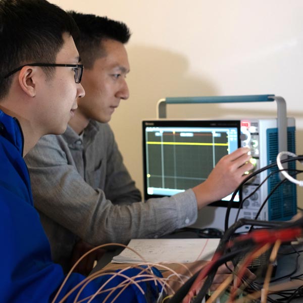 Rice graduate students Joshua Chen, left, and Zhanghao Yu test a prototype neural implant that can be programmed and charged remotely with a magnetic field.