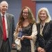 Three people standing in a row holding an award